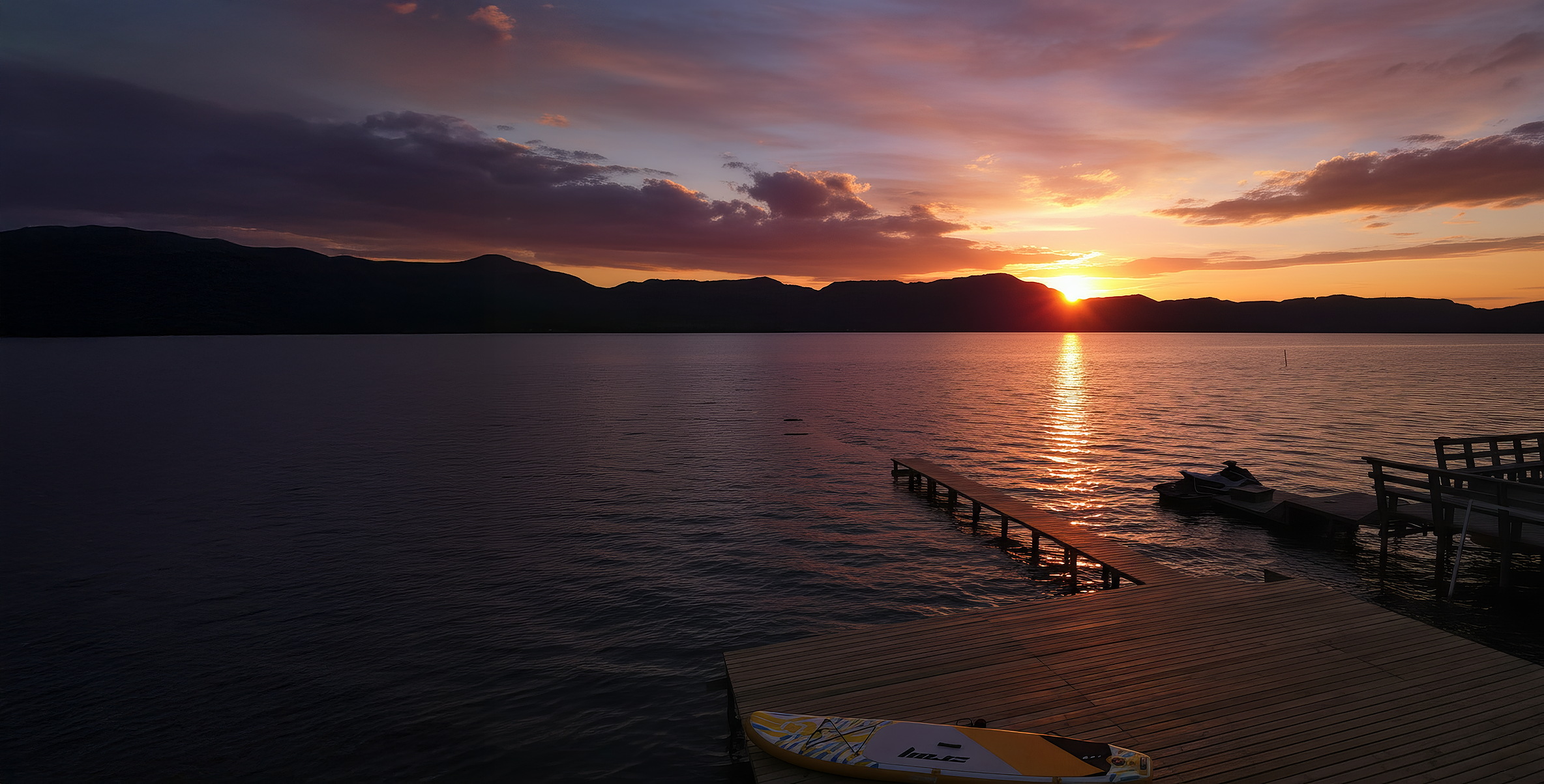 Atardecer en el lago con muelle de madera y kayak